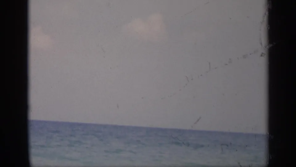 1959 California 8mm frame showing a calm ocean horizon and pale sky, bordered by dark vertical film edges.