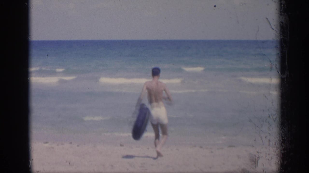 Man carries an inner tube while walking closer to the ocean waves.