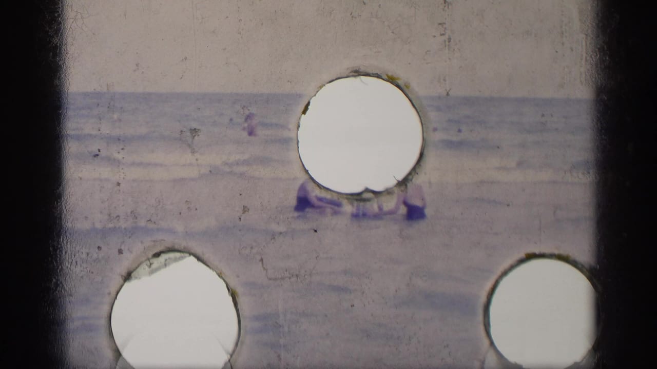 The beach action continues in a soft 8mm frame, with swimmers near the waterline partly hidden by bright circular contact-sheet artifacts.