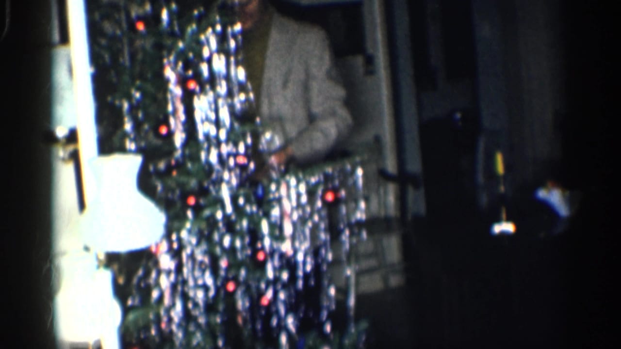 Tinsel Christmas tree fills the frame with a partially visible man behind it.
