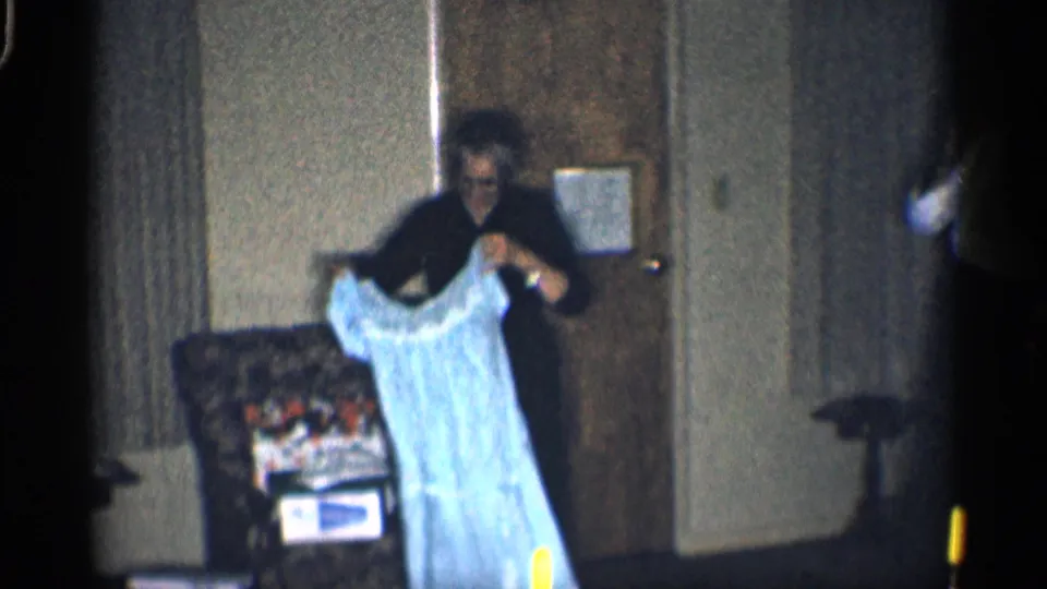 Inside the California home, the woman lifts a light blue dress in front of the patterned armchair after opening the gift.