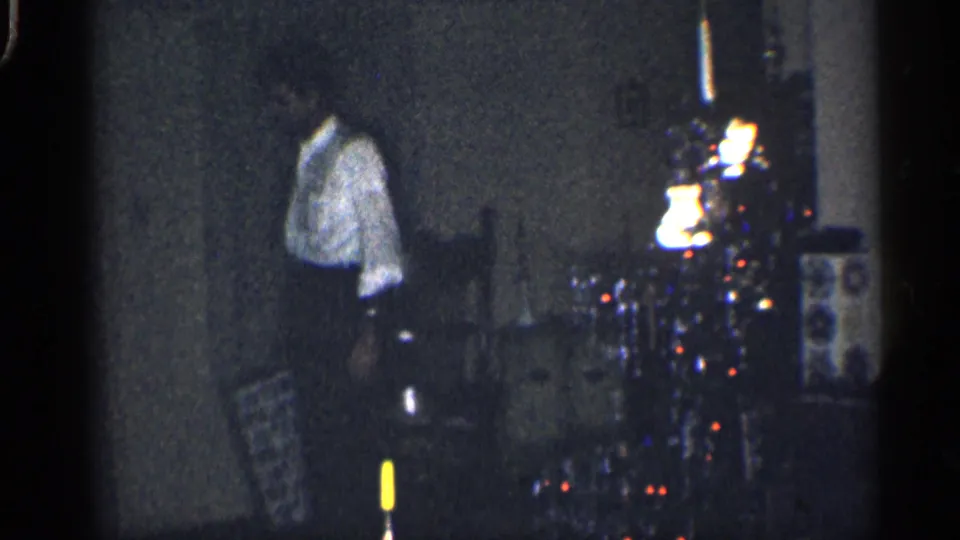 A man in a white shirt appears in profile near a glowing Christmas tree inside a private California home interior.