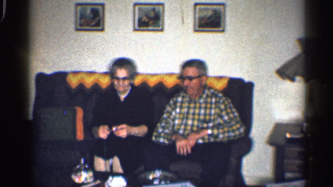 Older woman and older man seated together on a couch in a living room.