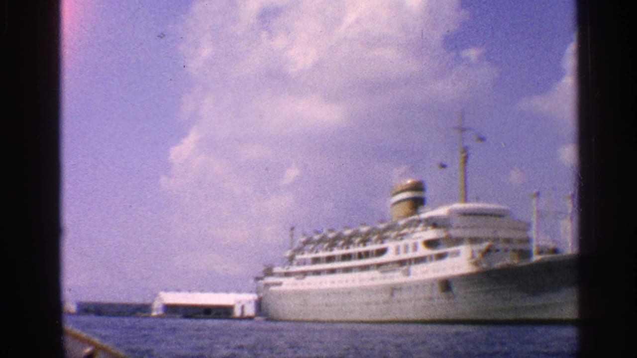 White ocean liner at dock with sky, water, and dark film border visible.