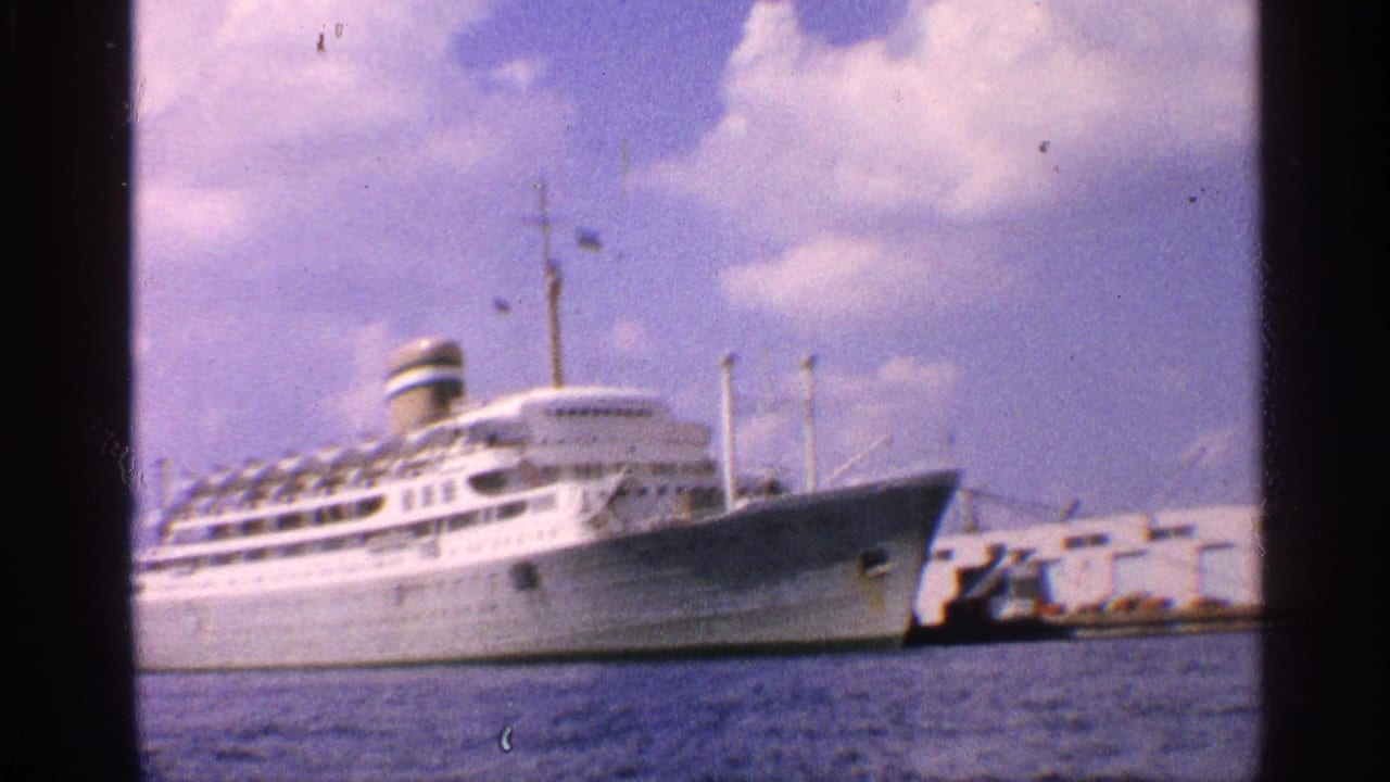 1959 California home-movie frame showing a white ocean liner moored at port, seen from across the water.