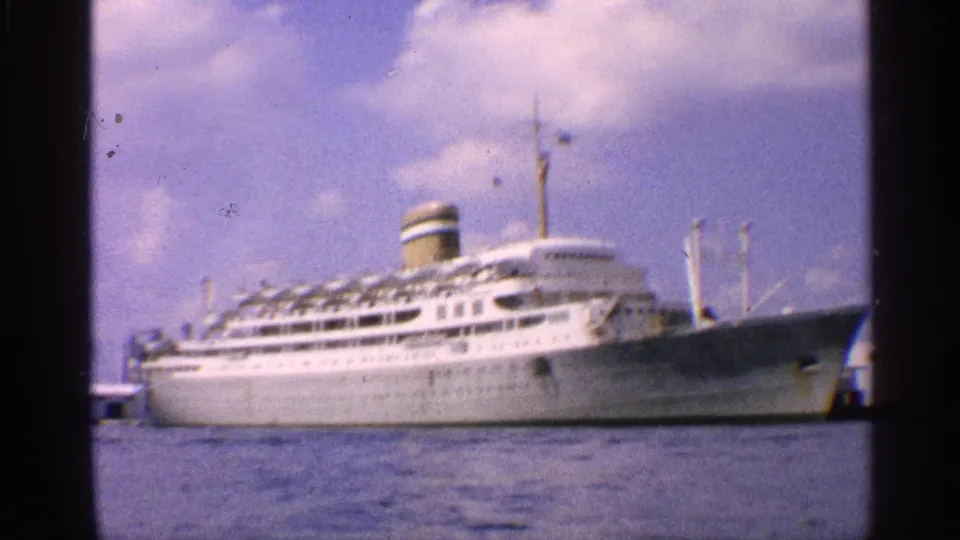 1959 California harbor view of a white docked passenger ship, with funnel and mast details visible through soft 8mm color.