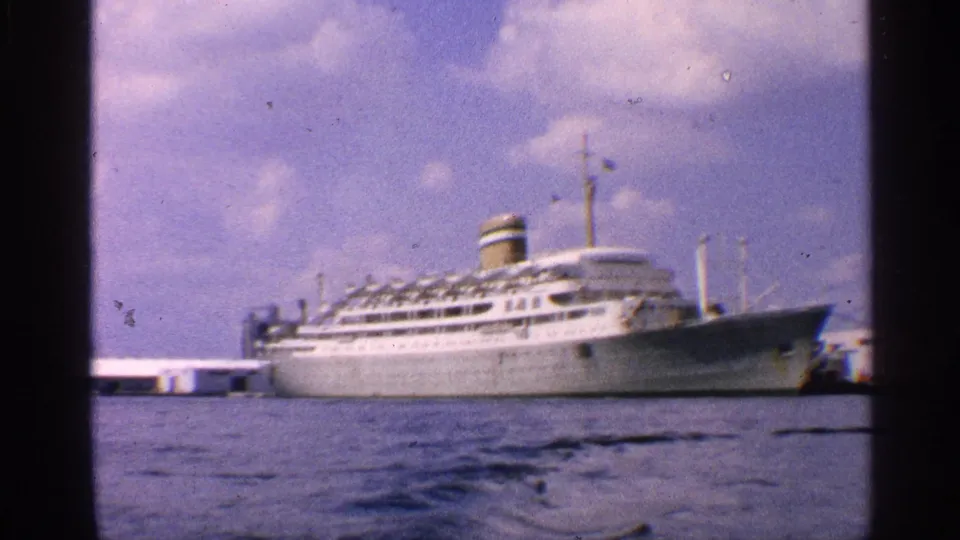 End frame of a 1959 California harbor shot, showing a white passenger ship docked across blue water under scattered clouds.