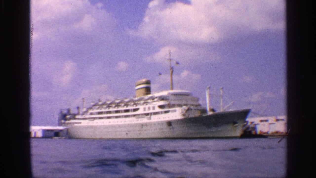 1959 California harbor view with a white ocean liner moored at a waterfront pier, seen across rippling water.