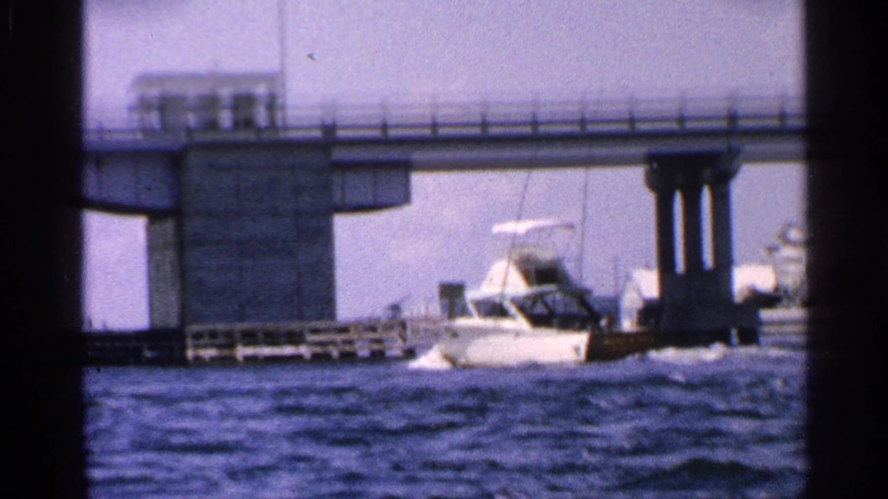 Motorboat on rough water beside a concrete bridge support and railings.