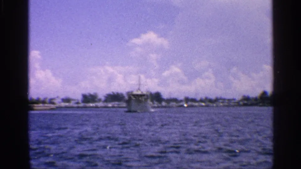 1959 California home-movie frame looking across rippling water toward a distant boat and low shoreline.
