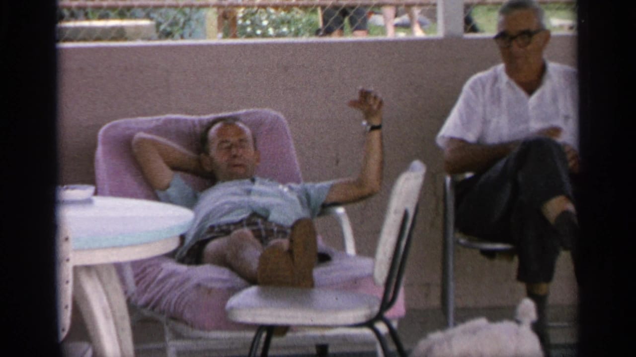 Man reclining on a pink patio lounge chair while another man sits nearby.