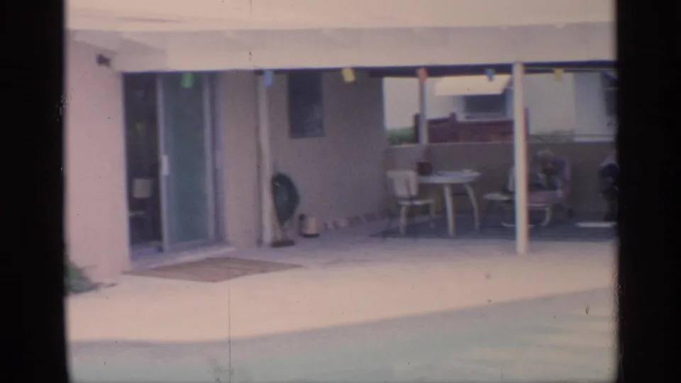 A wider 1959 Florida patio view shows sliding doors, patio furniture, a covered area, and the edge of the swimming pool.