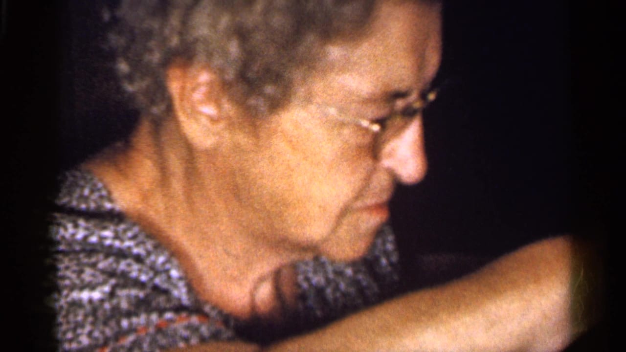 Older woman with glasses shown in profile with her arm raised nearby.