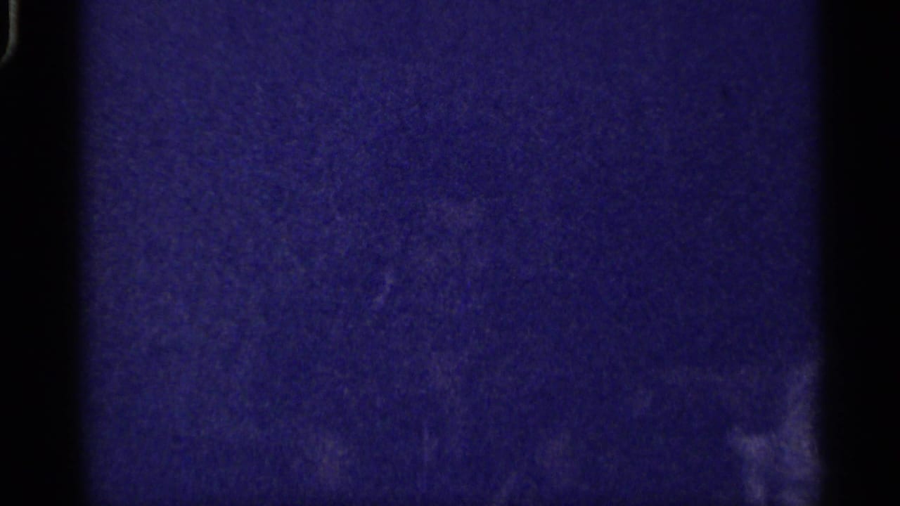 Florida-labeled 1959 8mm frame showing a very dark interior with blue cast, grain, and indistinct wall or room shapes.