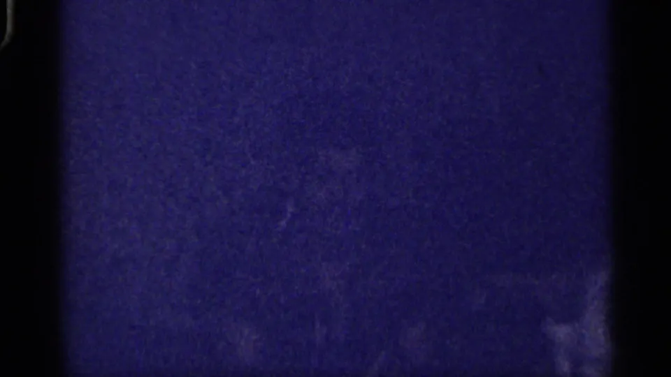 Florida-labeled 1959 8mm frame showing a very dark interior with blue cast, grain, and indistinct wall or room shapes.
