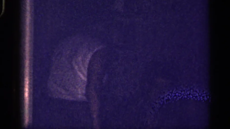 Florida-labeled 1959 home-movie frame with a shadowed adult head shape near the right side in a dark private room.