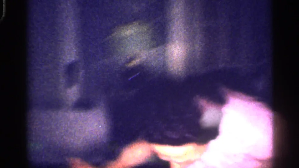 Grainy 1959 Florida home-movie frame showing people gathered indoors in dim light, partly obscured by blur and exposure.