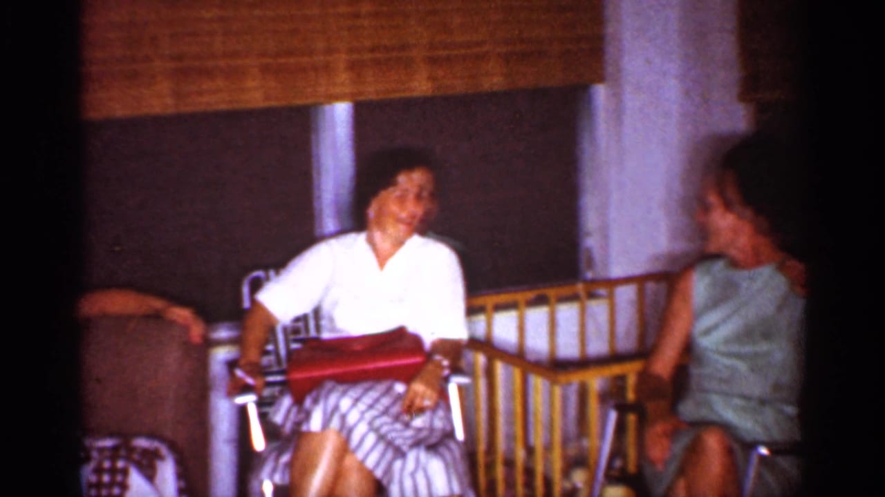 1959 Florida home-movie frame showing two women conversing in a likely hotel or vacation room.