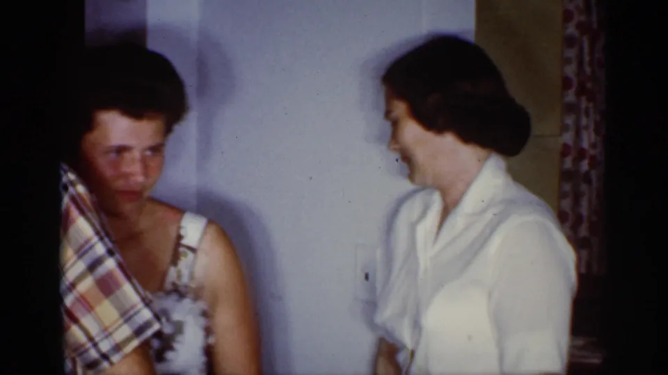 1959 Florida home-movie frame showing two women indoors during the birthday gathering, one looking toward the camera.