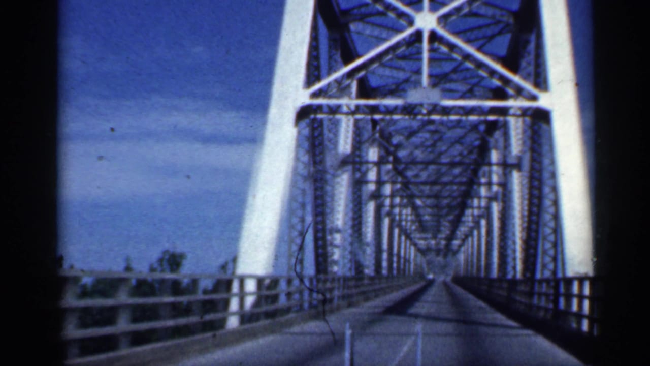 Windshield view as the car reaches the white-painted steel truss bridge in Indiana archival footage.