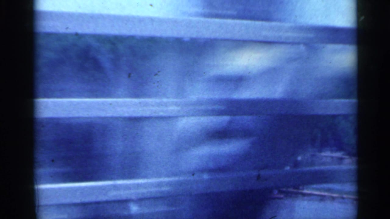 Blurred river view through a vehicle window with horizontal bars.