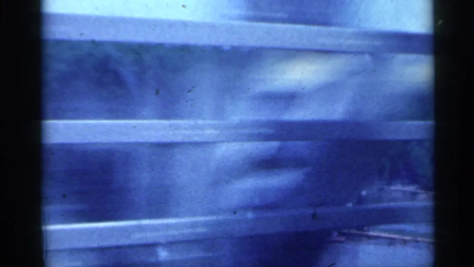 1959 Indiana 8mm frame looking through a moving vehicle window toward a wide river and distant shoreline.