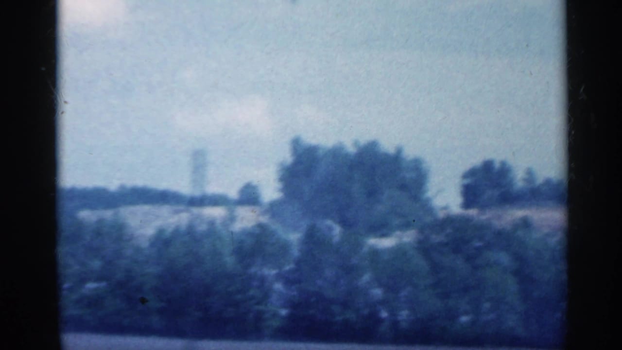 Drive-by view of Indiana countryside with tree clusters and open land, softened by 8mm motion blur.
