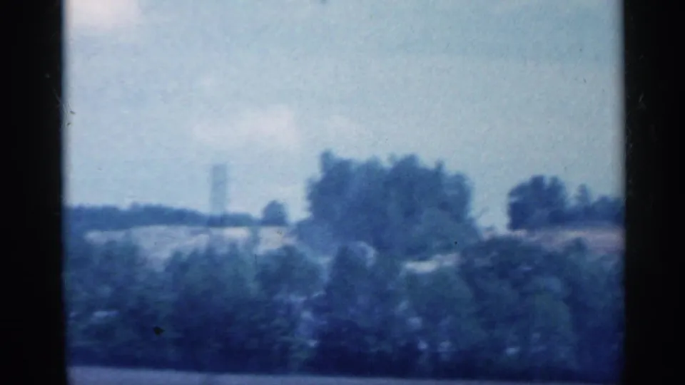 Drive-by view of Indiana countryside with tree clusters and open land, softened by 8mm motion blur.