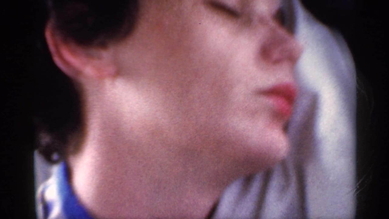 1959 Indiana home-movie frame showing a young man with eyeglasses resting in the passenger area of a moving car.