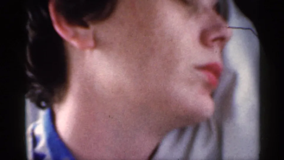1959 Indiana 8mm frame with a young man in eyeglasses seated in profile inside the car, filmed close from the passenger side.