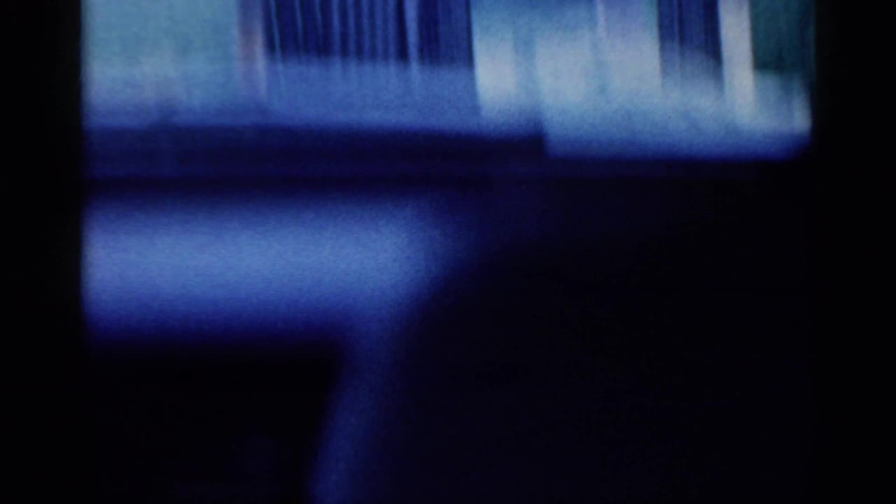 Dark, blurred interior frame with blue light and vertical window-like shapes.