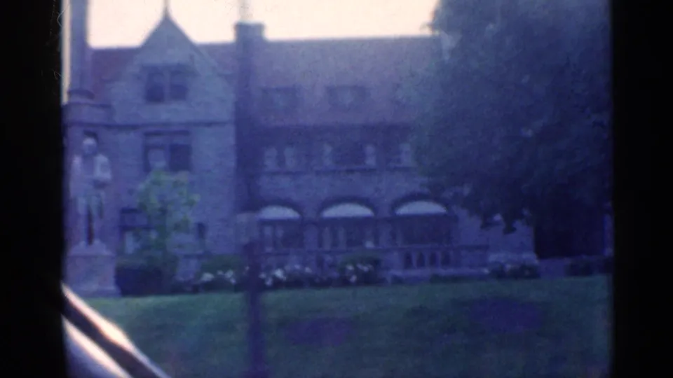 1959 Indiana frame showing a large stone building with arched windows, a lawn, trees, and a statue-like figure near the facade.