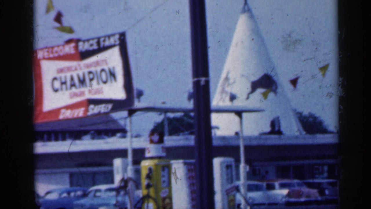 Fair sign beside a tent-like structure with parked cars below.