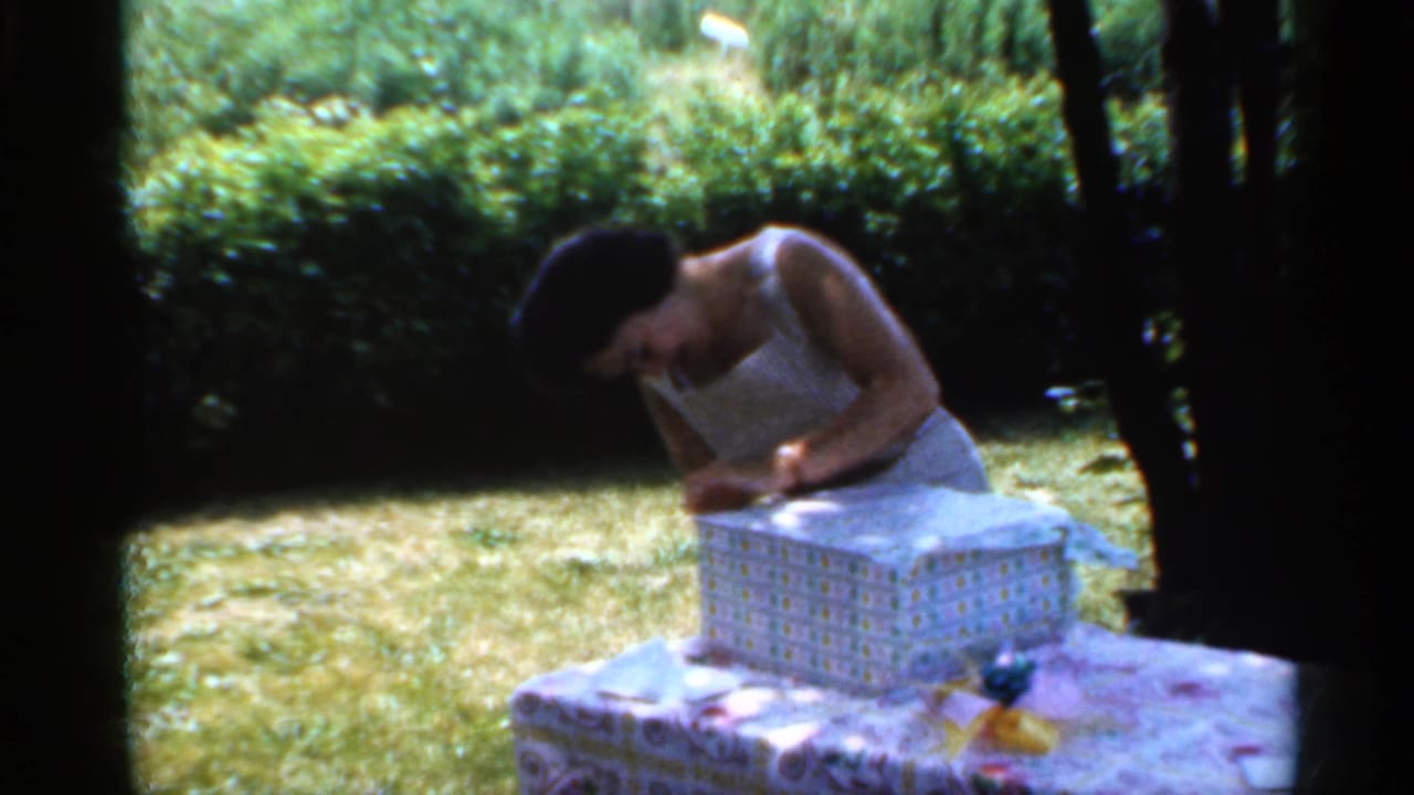Woman looks down while working at the lid or wrapping on a gift box outdoors.
