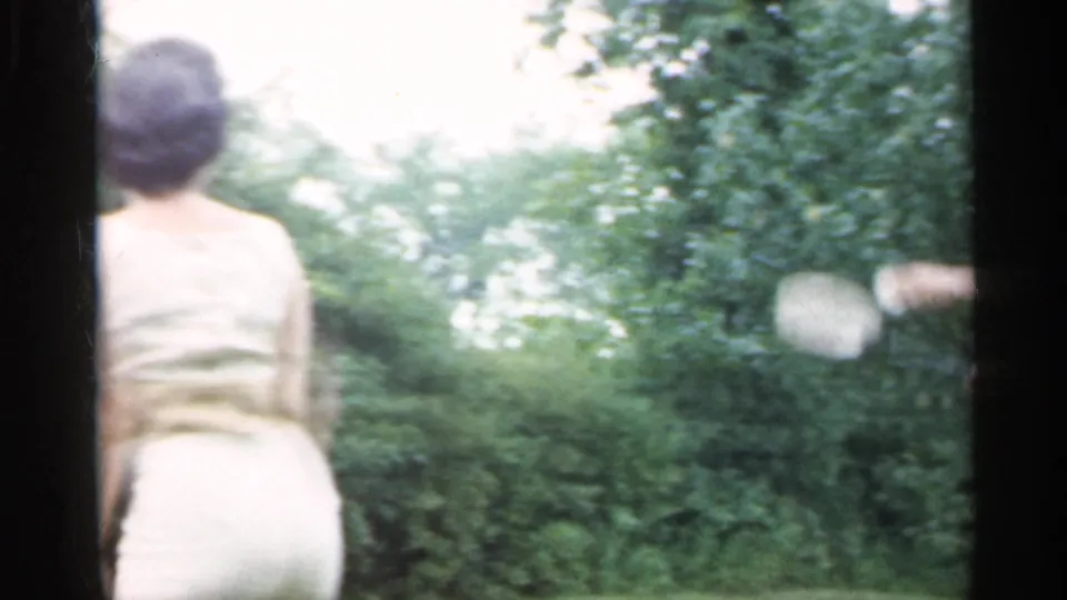In the 1959 Indiana backyard scene, a woman is seen from behind as a badminton racket swings into the frame from the side.