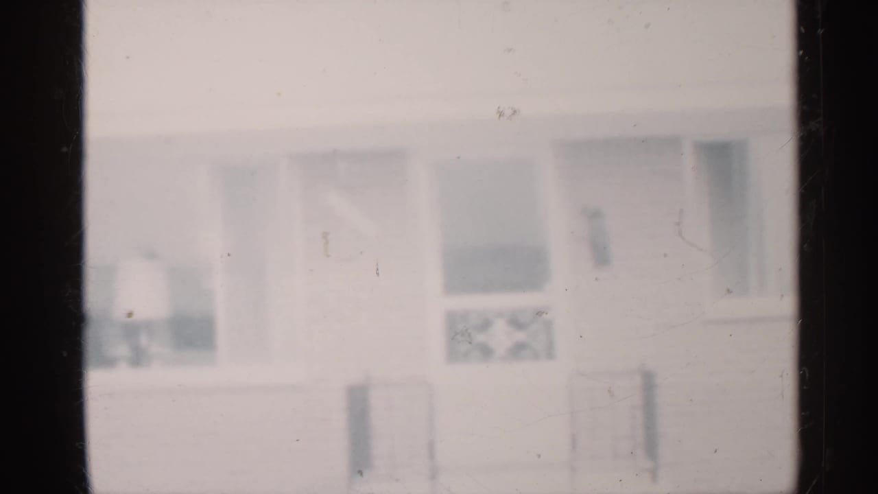 Blurry 1959 Indiana home-movie view of a house exterior with windows and porch details.
