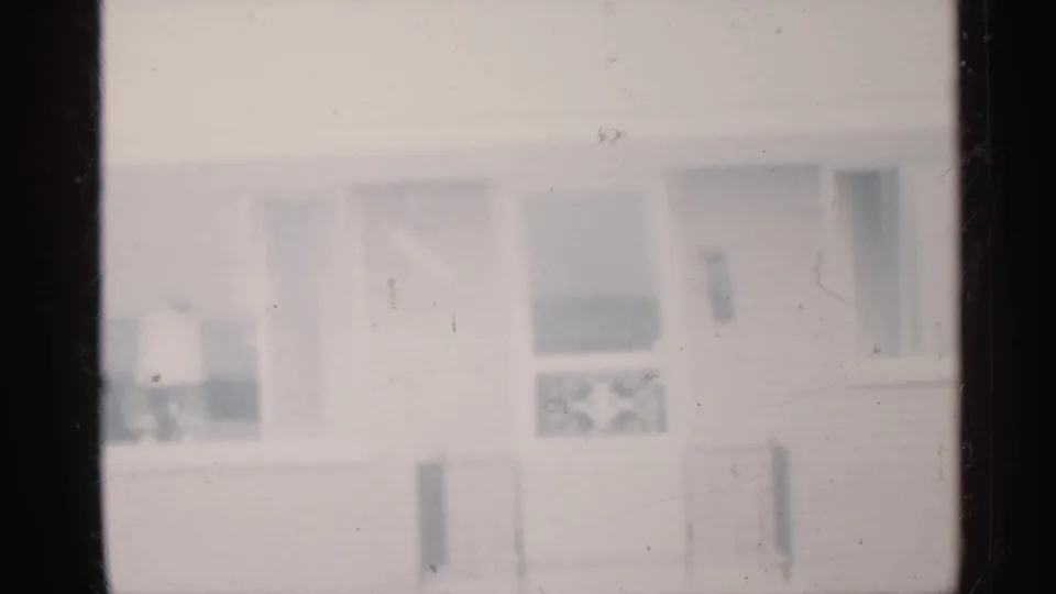 Blurry 1959 Indiana home-movie view of a house exterior with windows and porch details.
