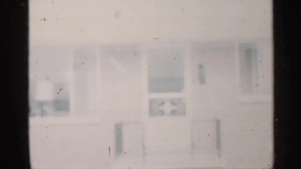 Blurry 1959 Indiana 8mm frame of a house exterior with visible windows, porch details, and film wear.
