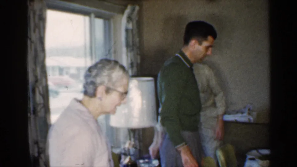 The final frame shows an older woman near a window and lamp while a man in a green sweater stands by the dining area in Indiana.