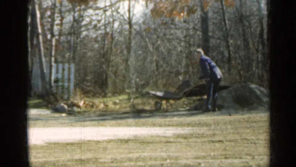 The final frame shows the man still working by the wheelbarrow and dirt pile, with the wooded yard and fence behind him.