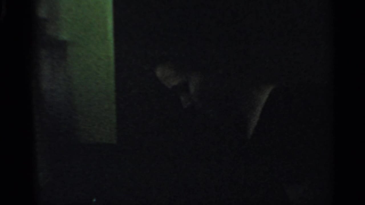 Dark interior with a shadowed person partly visible beside a lighter wall edge.