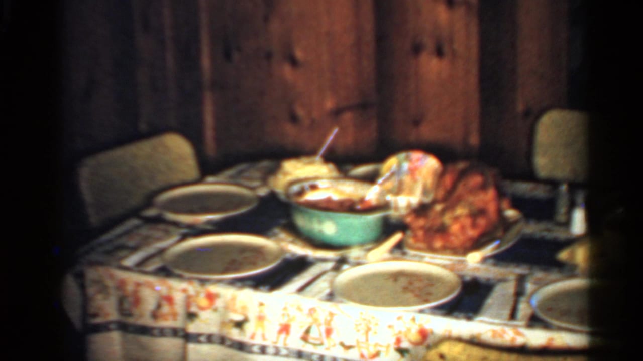 Dinner table with plates, bowls, and a roasted turkey in a wood-paneled room.