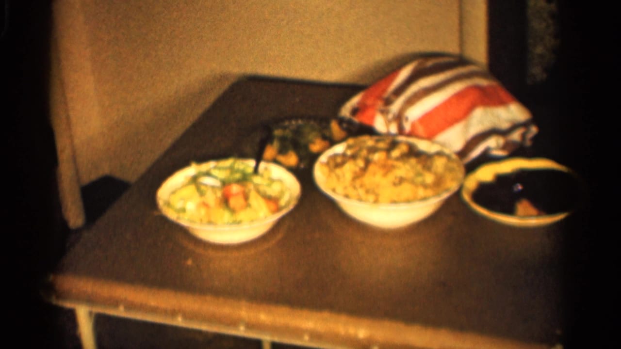 1959 Indiana home-movie frame showing prepared dishes on a side table inside a private home.