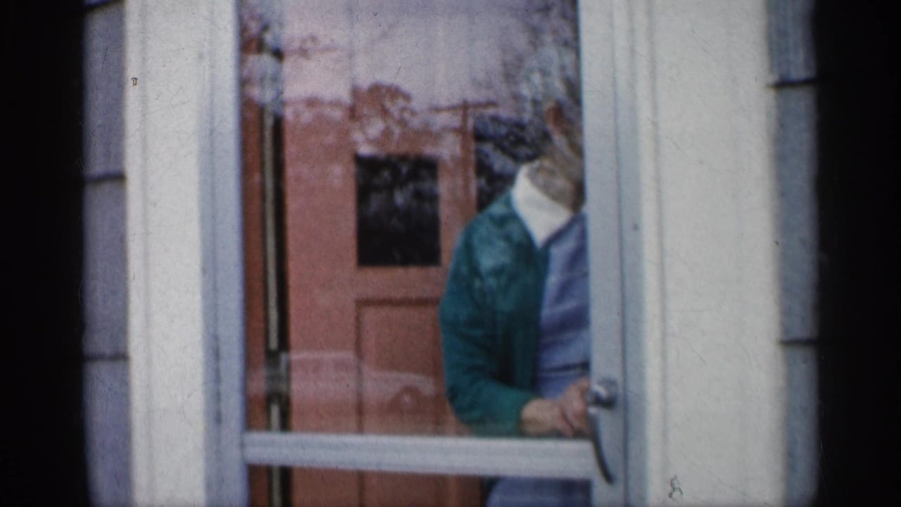 Woman looks downward while holding or moving through the screen door.