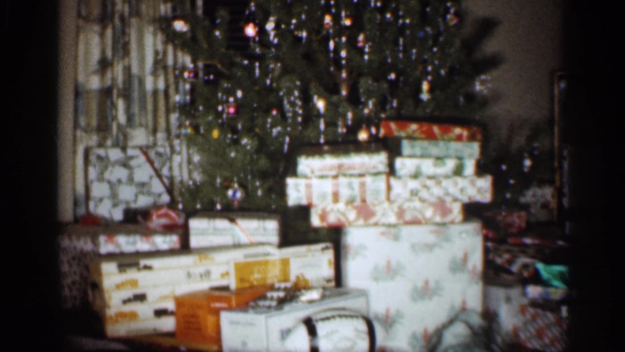 Decorated Christmas tree behind a pile of wrapped gift boxes.