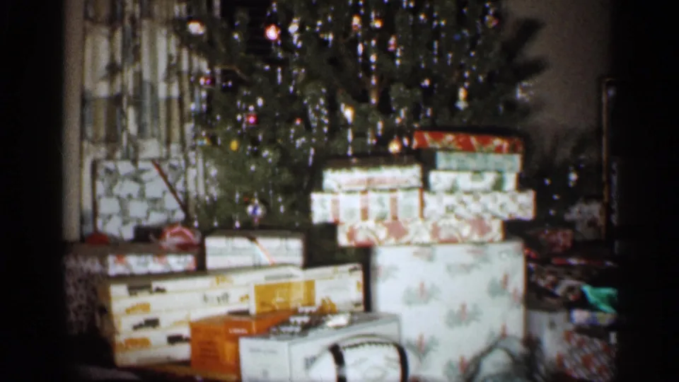 Wrapped presents fill the foreground while a decorated Christmas tree stands behind them in a 1959 Indiana home interior.