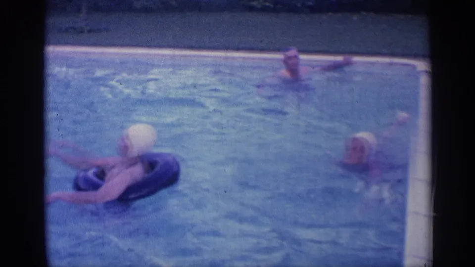 1959 Indiana pool frame with a woman in a white swim cap on a black ring and two adults swimming nearby.