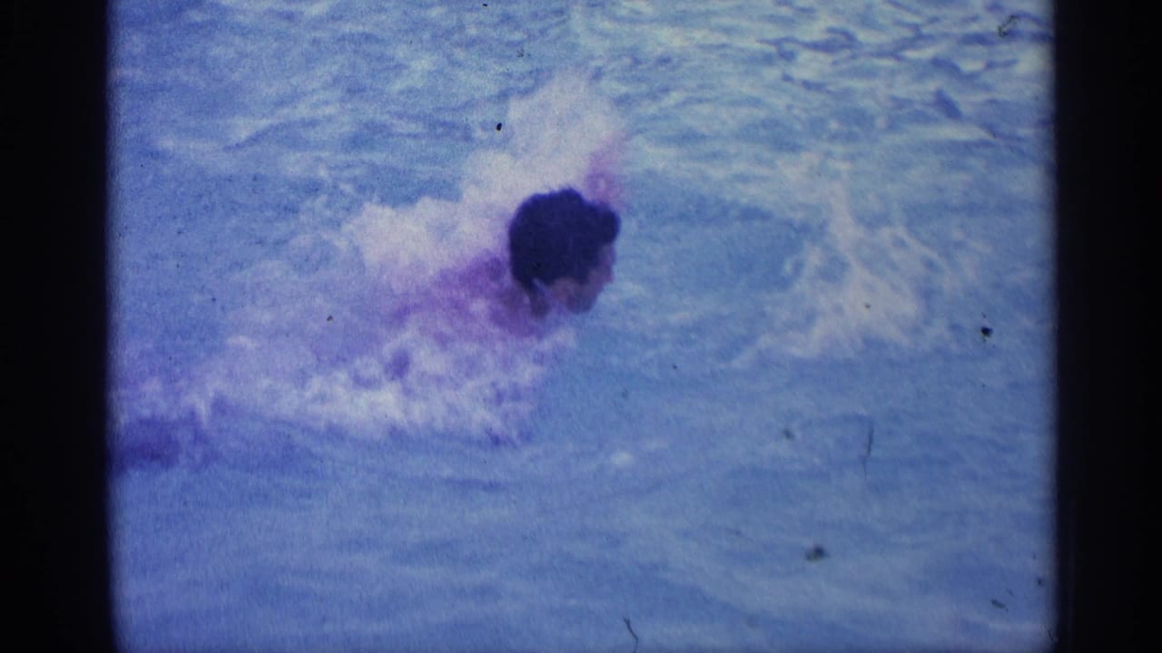 Man swimming through blue pool water with splashes around his head and shoulders.