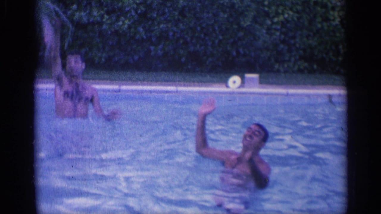 Two swimmers in pool water, one raising an arm while splashing.