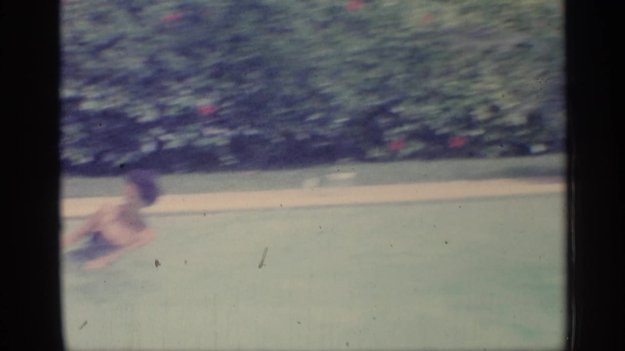 Soft 1959 Indiana pool frame with a swimmer moving across the water against a hedge-lined backyard setting.